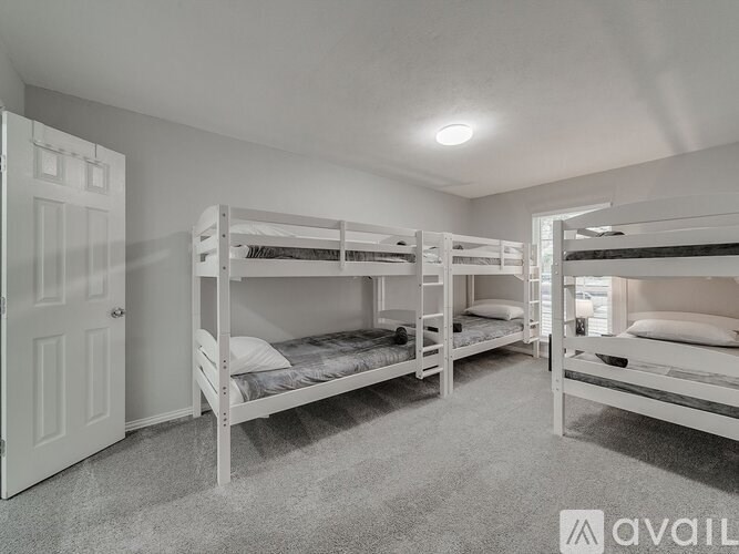 A room with white walls and carpet has three bunk beds.