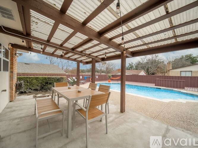 A patio with a table and chairs overlooking a pool.