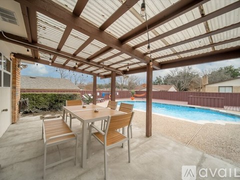 A patio with a table and chairs overlooking a pool.