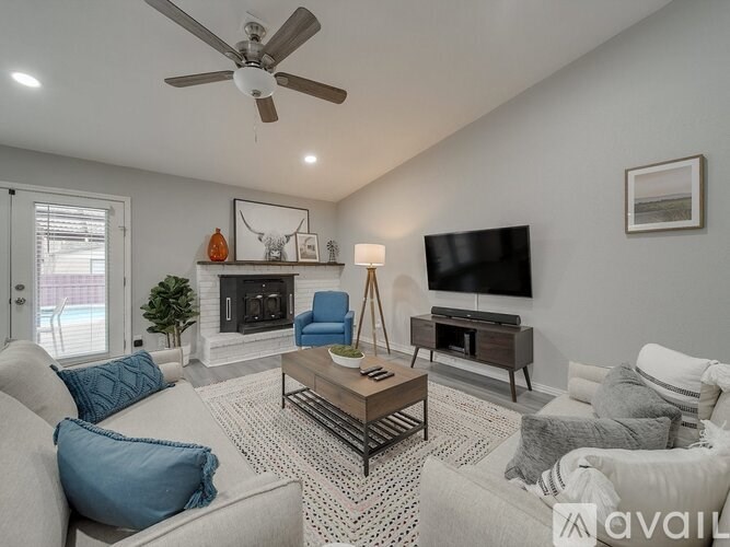 A living room with a fireplace, a television, and a ceiling fan.