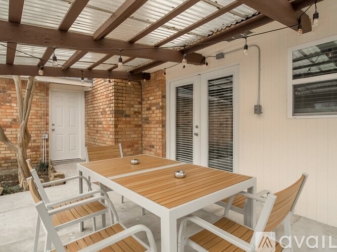 A wooden table with chairs under a roof with lights.