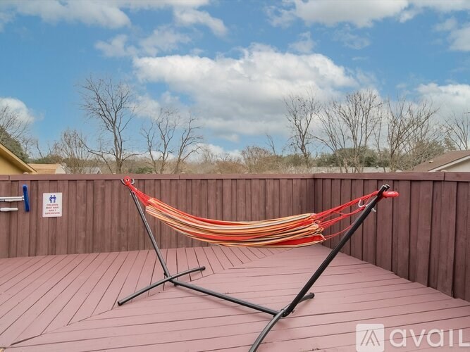 A hammock is strung between two poles on a wooden deck.