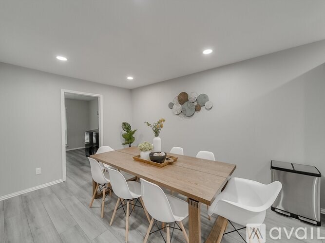 A dining room with a wooden table and white chairs.
