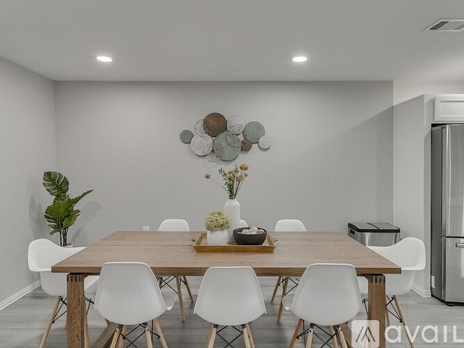 A modern dining room with a wooden table and white chairs.