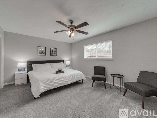 A bedroom with a bed, chair, and a ceiling fan.