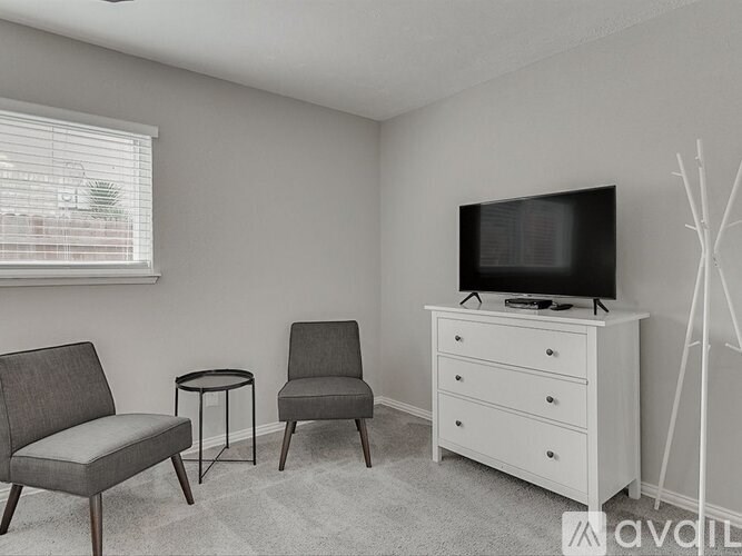 A living room with a grey chair, a black television, and a white cabinet.