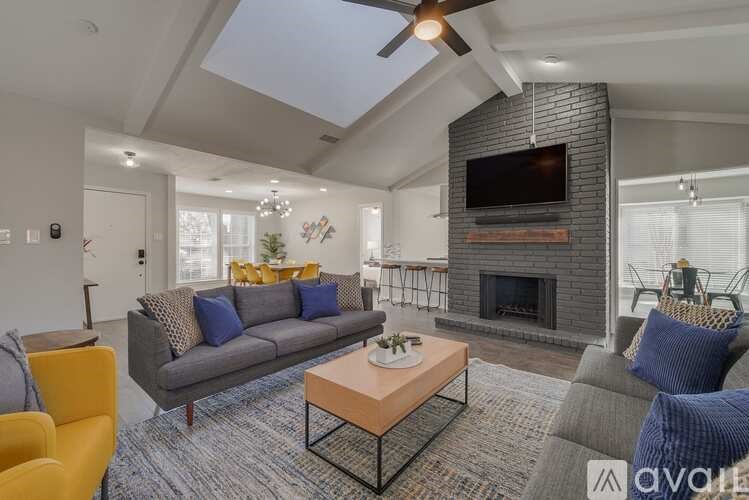 A living room with a grey couch, a yellow chair, a coffee table, and a fireplace.