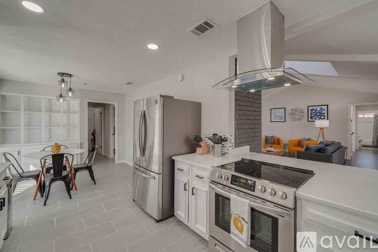 A modern kitchen with white appliances and a dining table set for four.