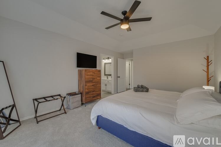 A bedroom with a bed, dresser, and ceiling fan.