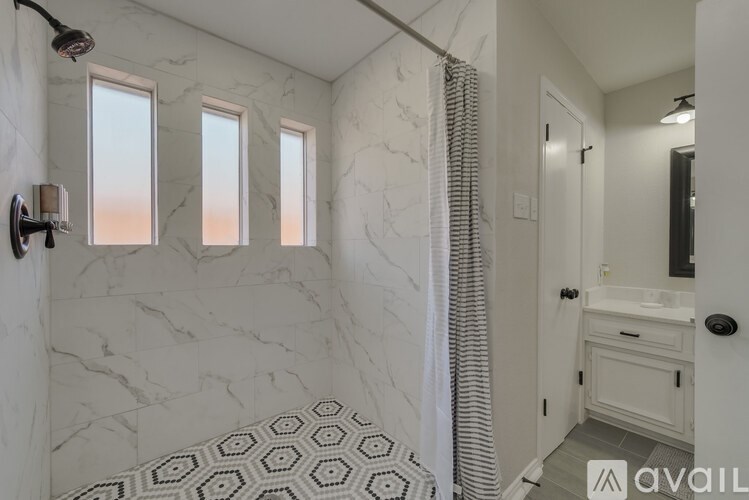 A bathroom with marble walls and a hexagonal tile floor.