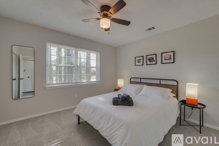 A bedroom with a bed, a ceiling fan, and two framed pictures on the wall.