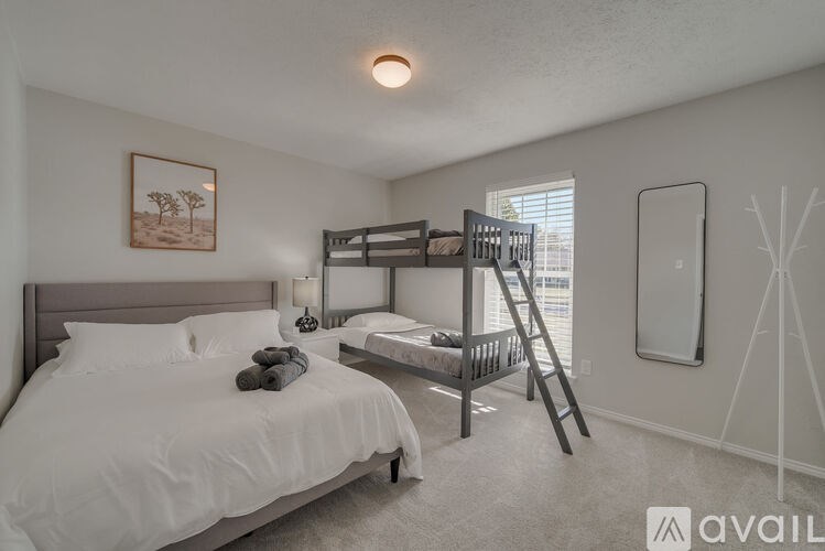 A bedroom with a white bed and a bunk bed with a ladder.