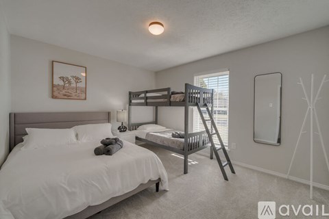 A bedroom with a white bed and a bunk bed with a ladder.