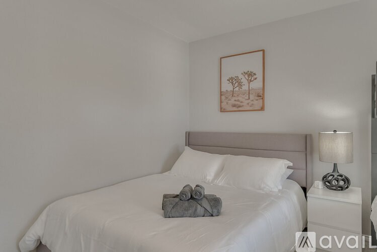 A bed with white sheets and a grey towel on it.