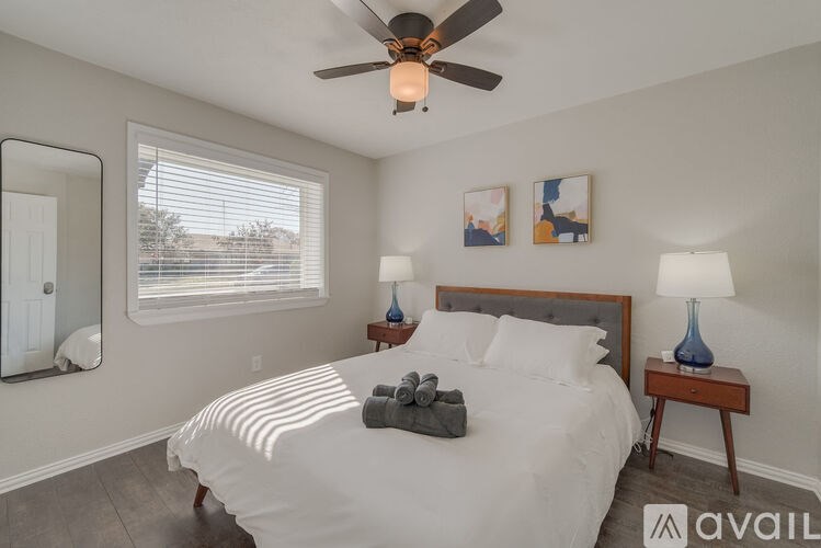 A bedroom with a large bed, a ceiling fan, and two lamps.