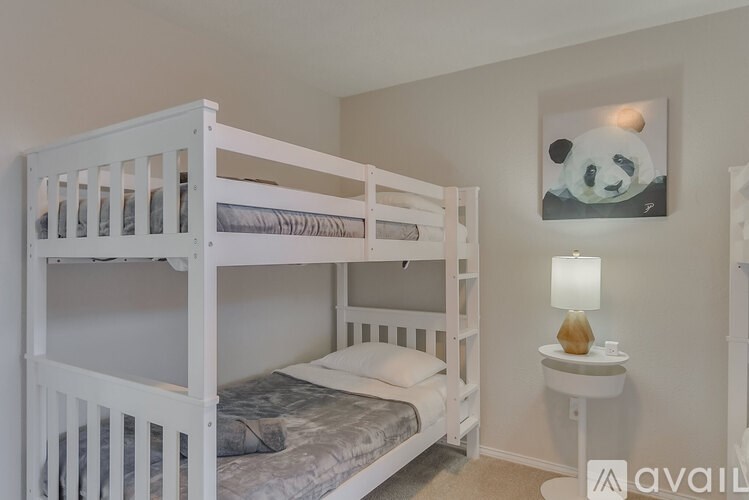A white bunk bed with a panda painting on the wall.