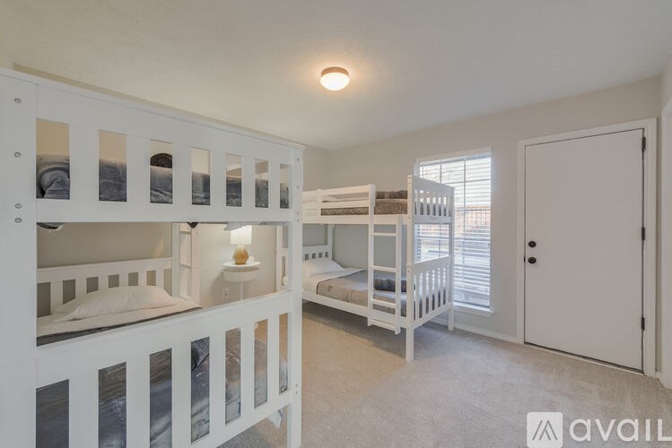 A white bunk bed with a single bed underneath it.