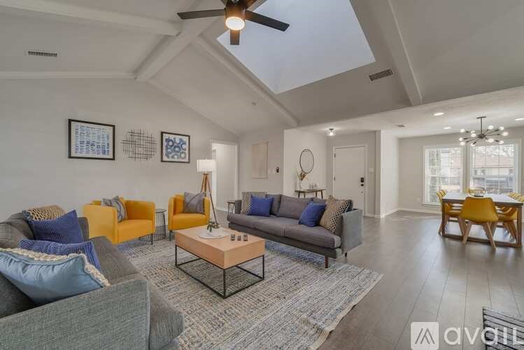 A living room with a grey couch, yellow armchairs, and a wooden dining table.