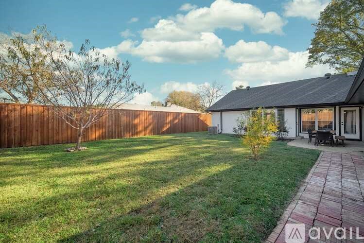 A house with a wooden fence and a tree in the yard.