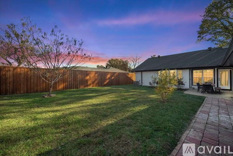 A house with a wooden fence and a tree in the yard.