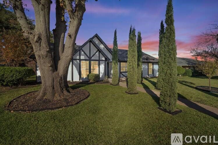 A house with a large tree in front and a smaller tree to the right.