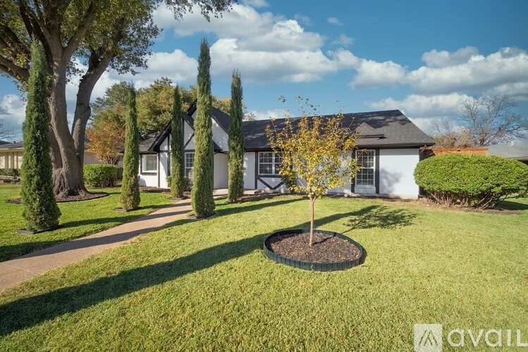 A house with a well-manicured lawn and a young tree in the foreground.