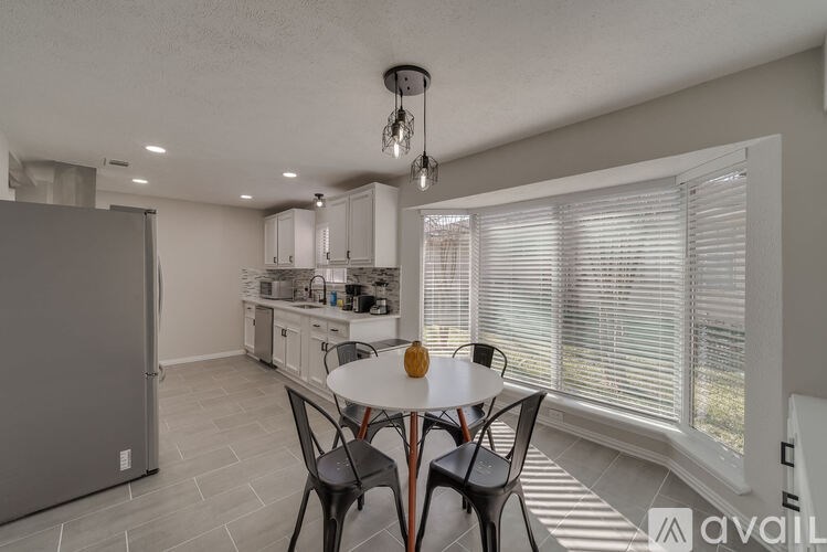 A kitchen with a table and chairs in front of a window.