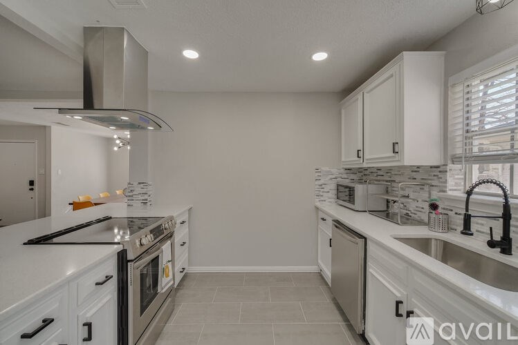 A modern kitchen with a stainless steel stove and white cabinets.