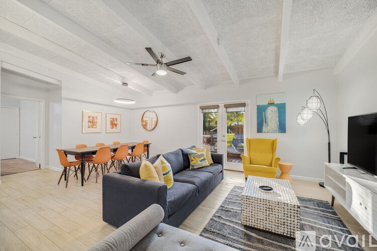 A living room with a grey couch, a yellow chair, and a television.
