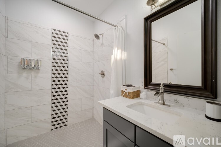 A bathroom with a white tiled shower and a white sink.