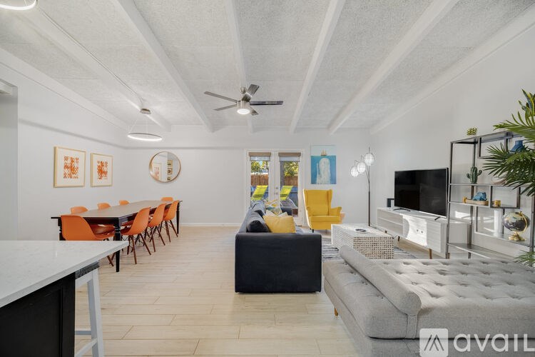 A living room with a grey sofa, orange chairs, and a television.