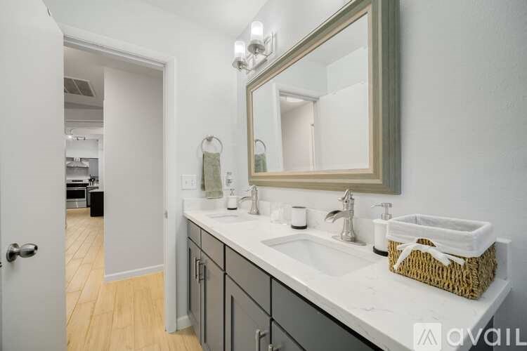 A bathroom with a sink, mirror, and a basket on the counter.