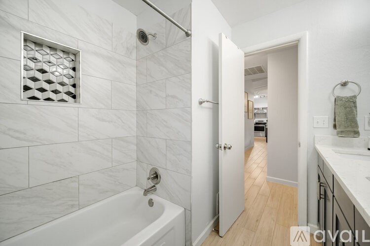 A bathroom with a white tub and a white tiled wall.