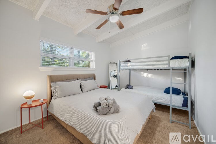 A bedroom with a bed, a ceiling fan, and a bunk bed.