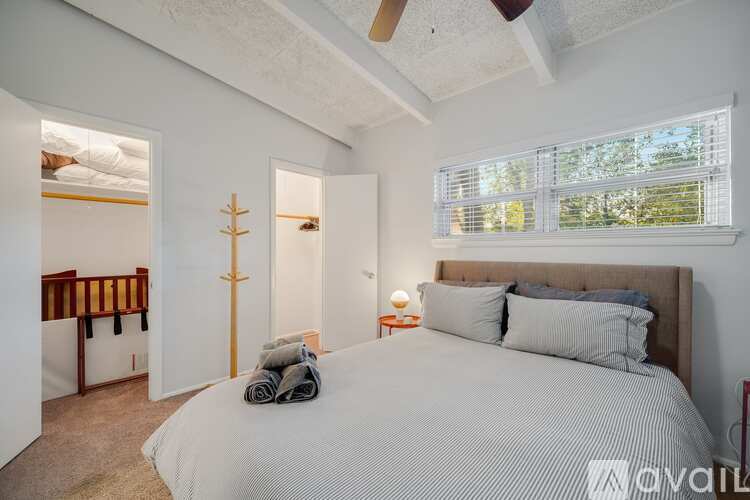 A bedroom with a large bed and a window with blinds.