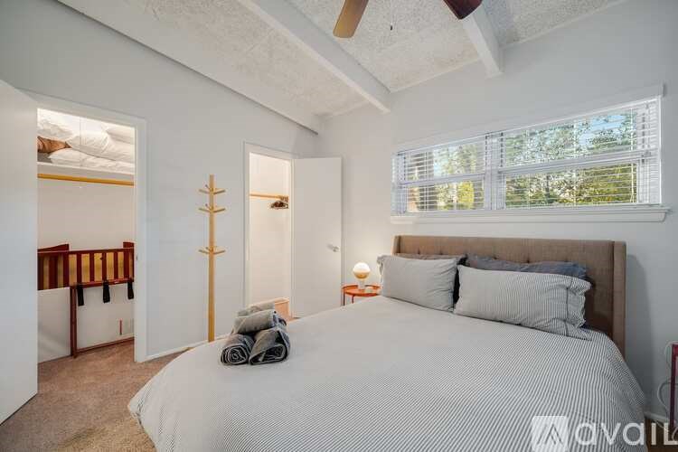 A bedroom with a large bed and a window with blinds.