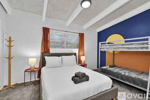 A bedroom with a large bed and a window with blinds.