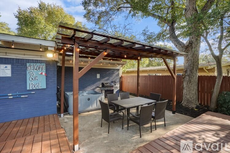 A wooden deck with a table and chairs under a pergola.