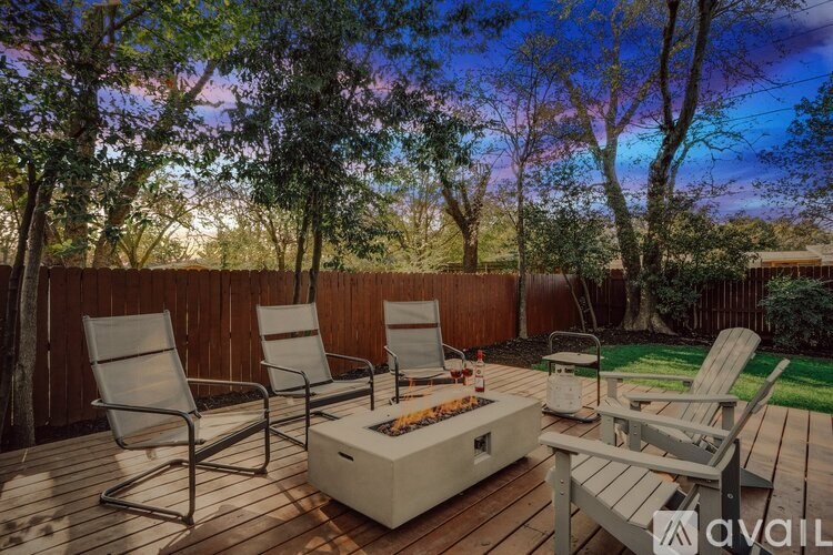 A patio with chairs and a grill is set up on a wooden deck.