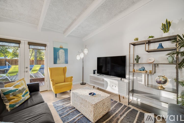 A living room with a television, yellow chair, and a glass shelf.