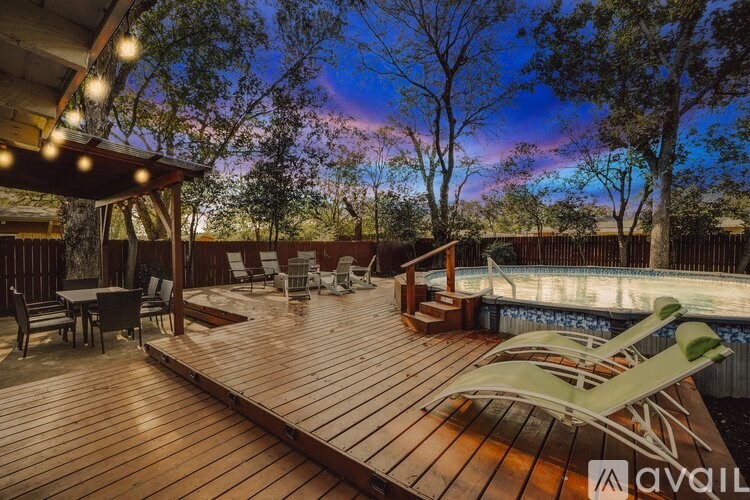 A wooden deck with chairs and a table is lit up at dusk.