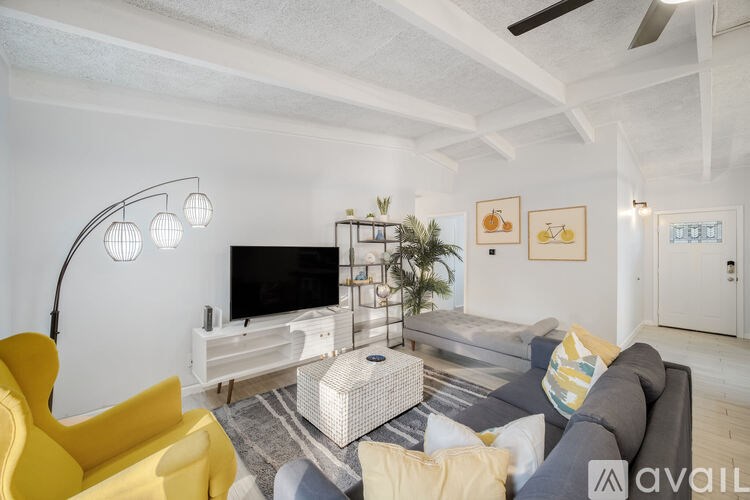 A living room with a yellow chair and a grey couch.