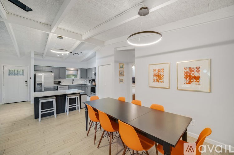 A modern dining room with a long table and orange chairs.