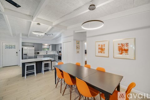 A modern dining room with a long table and orange chairs.