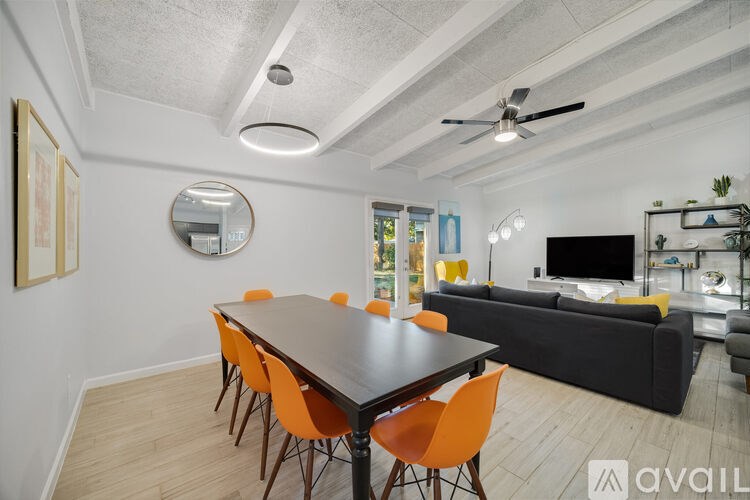A modern dining room with a large table and orange chairs.