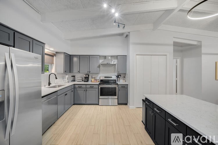 A modern kitchen with stainless steel appliances and wooden flooring.