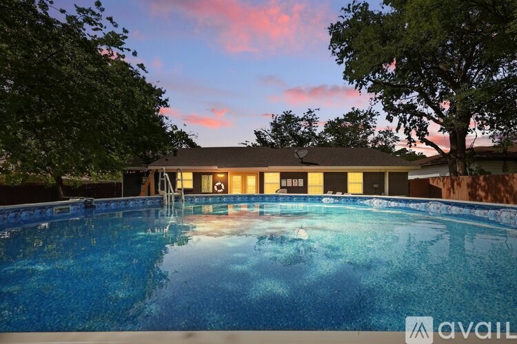 A pool with a house in the background during sunset.