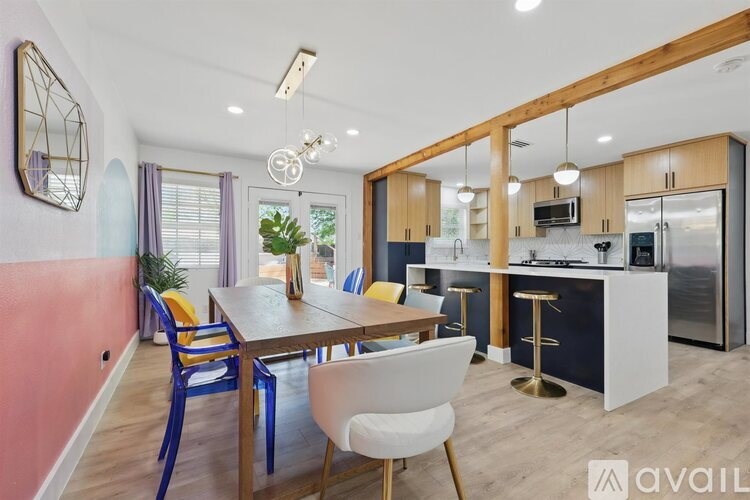 A kitchen with a dining table and chairs in the foreground and a refrigerator in the background.