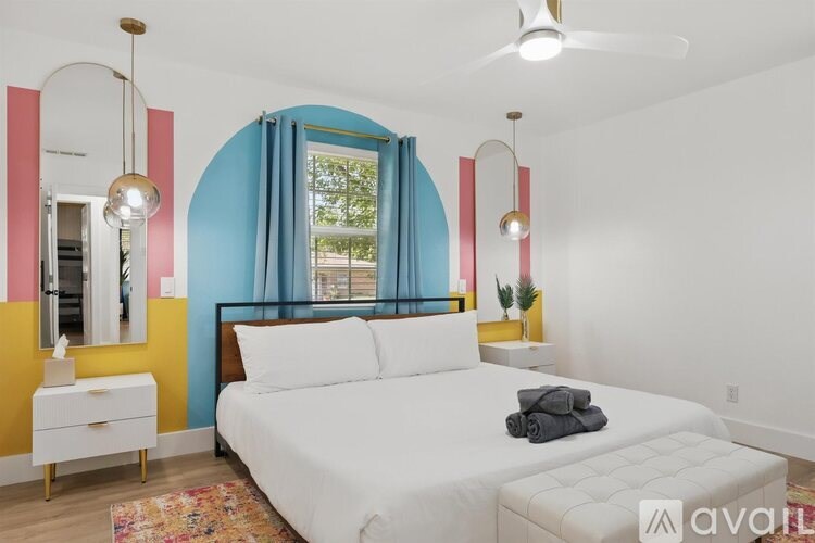 A bedroom with a white bed and a window with blue curtains.