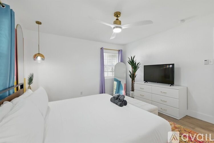 A bedroom with a bed, a television, and a plant.